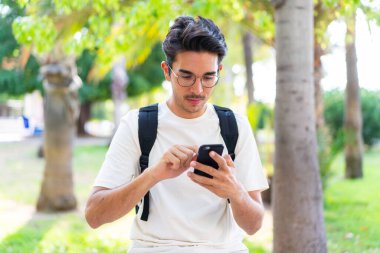 Dışarıda cep telefonu kullanan genç bir öğrenci.