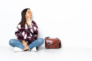 Genç bir bayan yerde oturuyor. Durma hareketi yapıyor ve hayal kırıklığına uğruyor.