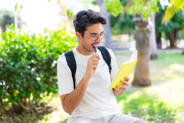 Dışarıda elinde bir defter tutan genç bir öğrenci.