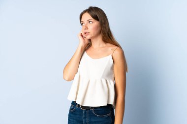 Mavi arka planda izole edilmiş genç Litvanyalı kadın biraz gergin.