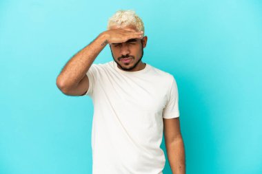 Genç Kolombiyalı yakışıklı adam mavi arka planda başağrısı ile izole