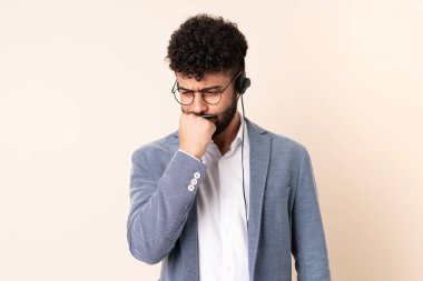 Faslı bir pazarlamacı bej arka planda izole edilmiş bir kulaklıkla çalışıyor. Şüpheleri var.