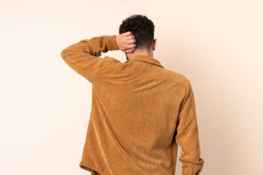 Faslı genç bir adam arka plandaki bej arka planda izole edilmiş ve düşünüyor.