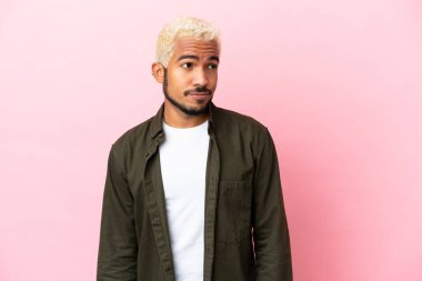 Pembe arka planda izole edilmiş genç Kolombiyalı yakışıklı bir adam.