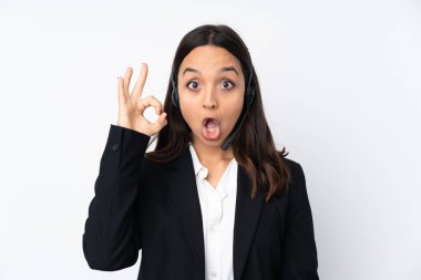 Beyaz arka planda izole edilmiş genç pazarlamacı kadın şaşırmış ve iyi işaretler gösteriyor.
