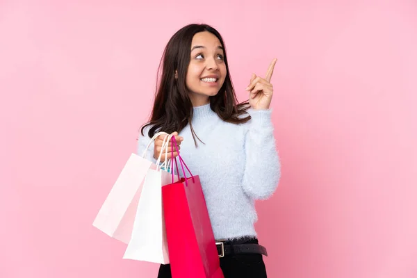 若いです女性とともにショッピングバッグ以上隔離されたピンクの背景PointingとともにザIndex指A素晴らしいアイデア — ストック写真