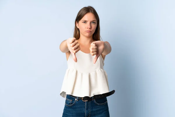 stock image Young Lithuanian woman isolated on blue background showing thumb down with two hands