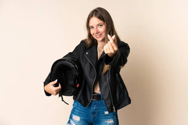若いですリトアニアの女性を保持していますオートバイヘルメット絶縁上ベージュ背景作るお金ジェスチャー — ストック写真
