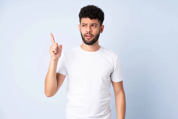 stock image Young Moroccan man isolated on blue background intending to realizes the solution while lifting a finger up