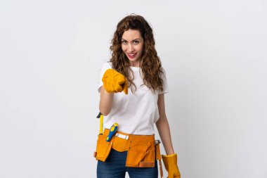 Beyaz arka planda izole edilmiş genç elektrikçi şaşırmış ve ön tarafı işaret ediyor.