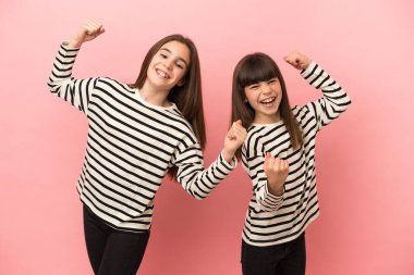 Pembe arka planda izole edilmiş küçük kız kardeşler zaferi kutluyorlar.