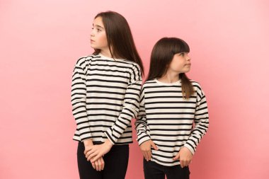 Küçük kız kardeşler pembe arka planda izole edilmiş gergin ve korkmuş