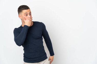 Beyaz arka planda izole edilmiş genç beyaz adam yan tarafa bakarken sürpriz jest yapıyor.