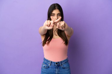 Mor arka planda izole edilmiş genç beyaz kadın bir hareketi durdurmak için eliyle jest yapıyor.