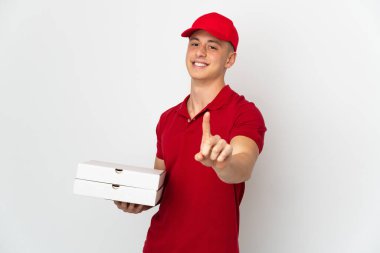 İş üniformalı bir pizzacı beyaz arka planda izole edilmiş pizza kutularını topluyor ve parmağını kaldırıyor.