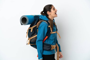 Arka planda büyük bir sırt çantası olan genç dağcı yan pozisyonda gülüyor.