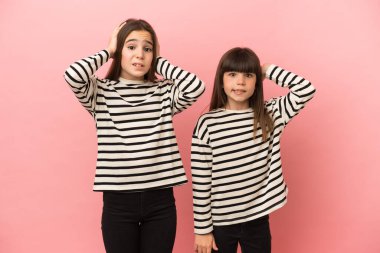 Küçük kız kardeşler pembe arka planda izole edilmiş migreni olduğu için el ele tutuşurlar.