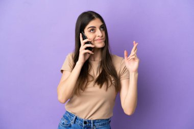 Mor arka planda izole edilmiş cep telefonu kullanan beyaz bir kadın.