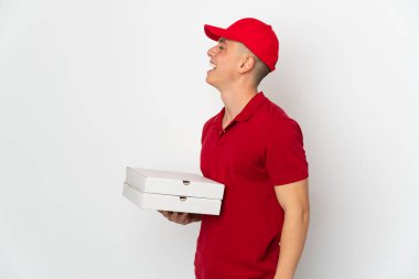 Pizza teslimatçısı üniformalı adam beyaz arka planda izole edilmiş pizza kutuları alıyor. Yan pozisyonda gülüyor.