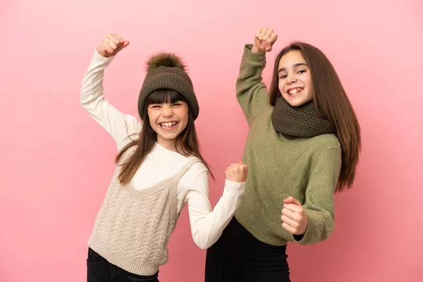 Hermanitas Vestidas Con Ropa Invierno Aisladas Sobre Fondo Rosa Celebrando —  Fotos de Stock
