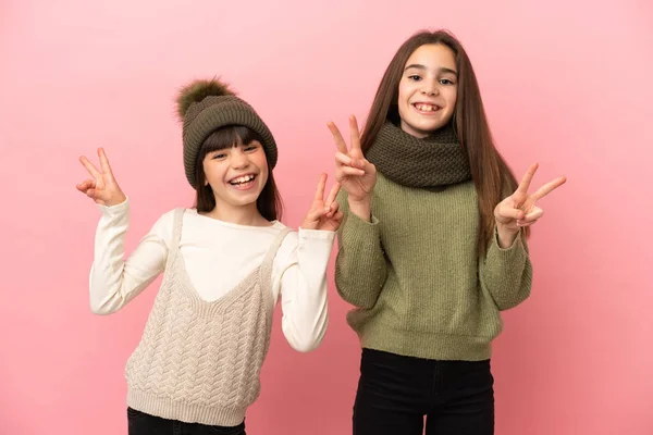 Hermanitas Vestidas Con Ropa Invierno Aisladas Sobre Fondo Rosa Sonriendo —  Fotos de Stock
