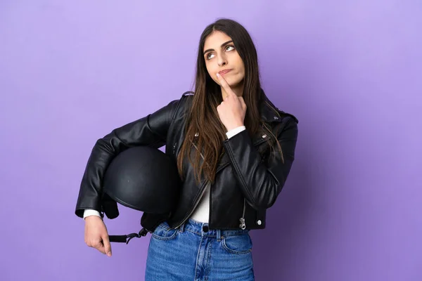 若いですCaucasian女性とともにオートバイヘルメット隔離上の紫の背景に疑問を持っています上を見ながら — ストック写真
