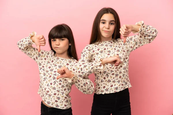 Hermanitas Niñas Aisladas Sobre Fondo Rosa Mostrando Pulgar Hacia Abajo —  Fotos de Stock