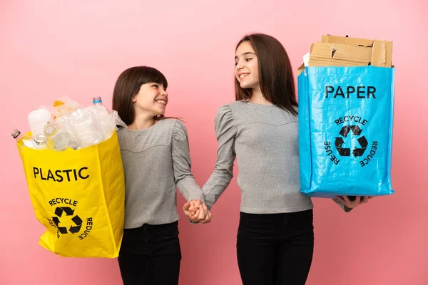 Små Systrar Återvinning Papper Och Plast Isolerad Rosa Bakgrund Handskakning — Stockfoto