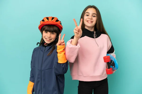 Hermanitas Practicando Ciclismo Patinadora Aisladas Sobre Fondo Azul Sonriendo Mostrando —  Fotos de Stock