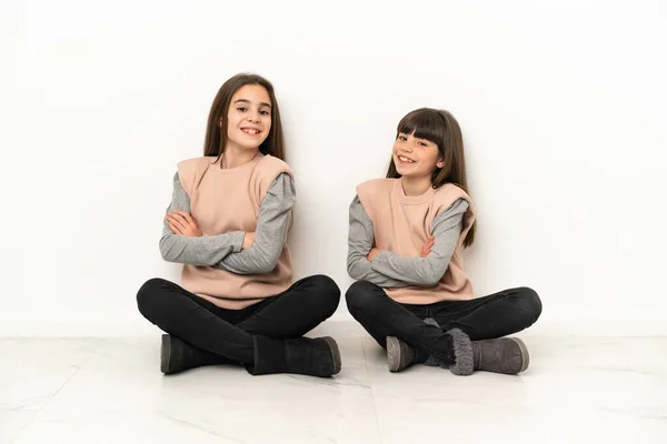 Μικρές Αδελφές Κάθονται Στο Πάτωμα Απομονωμένες Λευκό Φόντο Κρατώντας Χέρια — Φωτογραφία Αρχείου