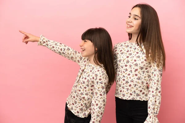 Hermanitas Niñas Aisladas Sobre Fondo Rosa Presentando Una Idea Mientras —  Fotos de Stock