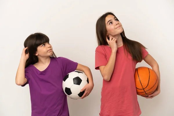 배경에서 축구와 농구를 자매들 머리를 긁으면서 아이디어를 생각하고 — 스톡 사진