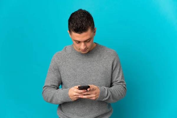 Jeune Homme Caucasien Isolé Sur Fond Bleu Utilisant Téléphone Mobile — Photo