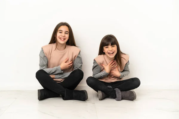 Irmãzinhas Sentadas Chão Isoladas Fundo Branco Sorrindo Muito Colocar Mãos — Fotografia de Stock
