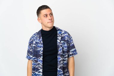 Beyaz arka planda izole edilmiş genç beyaz adam yukarı bakarken şüpheleri var.