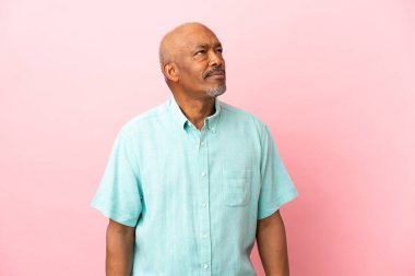 Kübalı son sınıf öğrencisi pembe arka planda izole edilmiş ve araştırılıyor