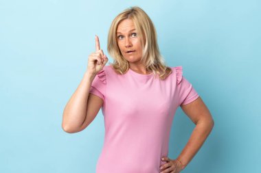 Orta yaşlı bir kadın, mavi arka planda izole edilmiş.