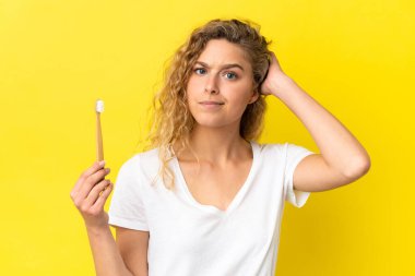 Sarı arka planda dişlerini fırçalayan beyaz bir kadın şüpheleri var.