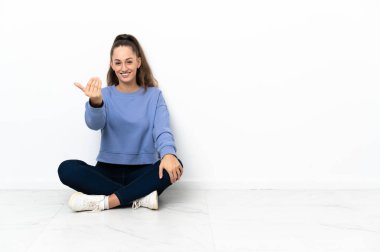 Yerde oturan genç kadın el ile gelmek için davet. Geldiğin için mutluyum.