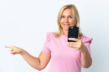 Beyaz arka planda izole edilmiş cep telefonu kullanan orta yaş şaşırmış ve parmağıyla kenarı işaret ediyor