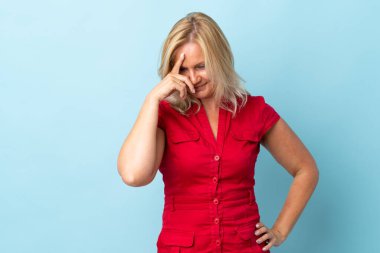 Mavi arka planda izole edilmiş orta yaşlı kadın gülüyor.