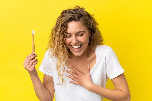 Młoda Biała Kobieta Trzyma Szczotkujące Zęby Odizolowane Żółtym Tle Uśmiechając — Zdjęcie stockowe
