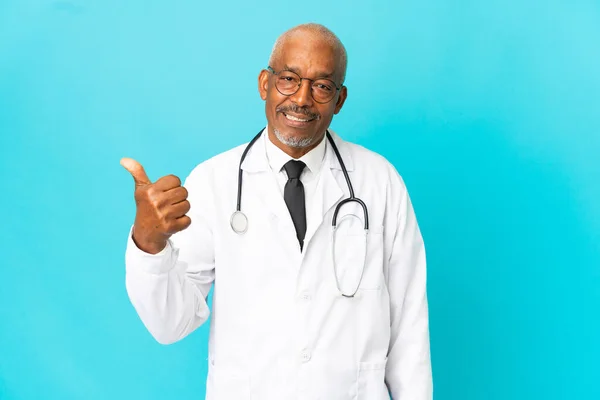 Starszy Lekarz Odizolowany Niebieskim Tle Wskazując Bok Aby Przedstawić Produkt — Zdjęcie stockowe