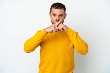 Beyaz arka planda izole edilmiş genç Brezilyalı bir adam sessizlik işareti gösteriyor.