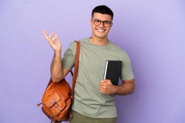 Tecrit edilmiş arka planda yakışıklı bir öğrenci. Davet edilmek için ellerini yana uzatıyor.