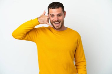 Beyaz arka planda izole edilmiş genç Brezilyalı bir adam telefon jesti yapıyor. Bana geri dönüş işareti ver.