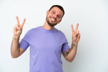 Beyaz arka planda izole edilmiş genç Brezilyalı iki eliyle zafer işareti gösteriyor.