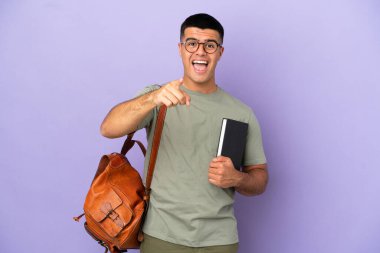 Soyutlanmış geçmişi olan yakışıklı öğrenci şaşırmış ve ön tarafı işaret ediyor.