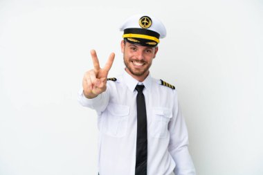 Brezilya uçağı pilotu beyaz arka planda izole edildi. Gülümsüyor ve zafer işareti gösteriyor.