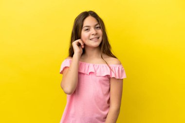 Sarı arka planda izole edilmiş küçük beyaz kız gülüyor.